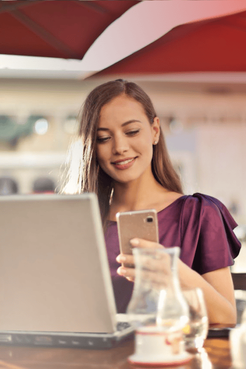 Glückliche Frau mit Mobiltelefon und Laptop
